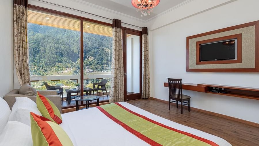 The photo displays a well appointed hotel room with a king size bed, plush bedding, and a cosy sitting area  | DLS Serenity Resort and Spa